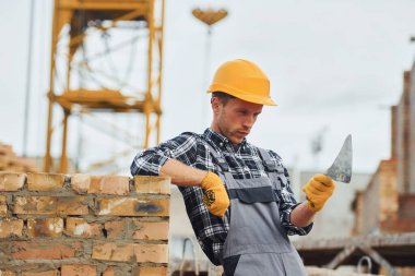 İnşaat için spatulayla birlikte. Üniformalı ve güvenlik ekipmanlı işçilerin inşaat işi var.