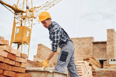 Construction worker in uniform and safety equipment have job on building.