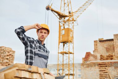 Üniformalı inşaat işçisi ve güvenlik ekipmanı inşaatında çalışıyor.