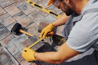 Ölçme işlemi. Sarı üniformalı erkek işçi kaldırımda çalışıyor..