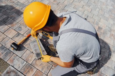 Ölçme işlemi. Sarı üniformalı erkek işçi kaldırımda çalışıyor..