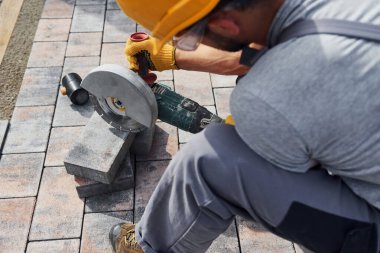 Manzarayı kapat. Sarı üniformalı erkek işçi kaldırımda çalışıyor..