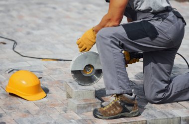 Manzarayı kapat. Sarı üniformalı erkek işçi kaldırımda çalışıyor..