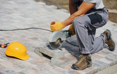 Manzarayı kapat. Sarı üniformalı erkek işçi kaldırımda çalışıyor..