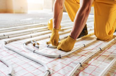 Bir sürü boru. Sarı üniformalı işçiler zemin altı ısıtma sistemi kuruyor.