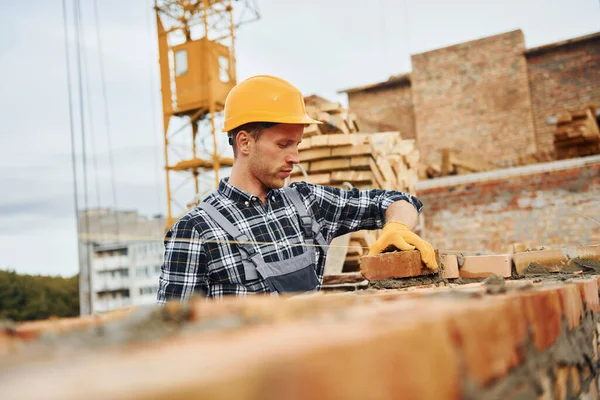 Laying bricks. Construction worker in uniform and safety equipment have job on building.