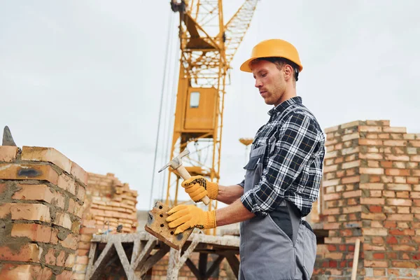 İnşaat için spatulayla birlikte. Üniformalı ve güvenlik ekipmanlı işçilerin inşaat işi var.