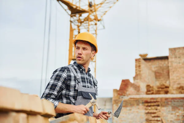 With spatula for construction. Worker in uniform and safety equipment have job on building.