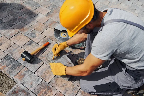 Sarı üniformalı erkek işçi kaldırımda çalışıyor..