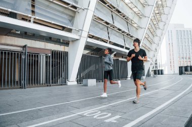 Avrupalı erkek ve Afrikalı Amerikalı kadın spor kıyafetleri içinde birlikte spor yapıyorlar..