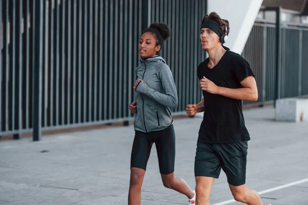 European man and african american woman in sportive clothes have workout together.