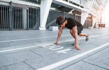 Spor elbiseli genç adam gündüz vakti dışarıda antrenman yapıyor..