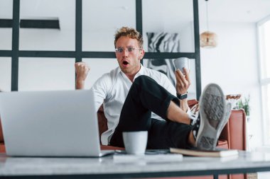 Dizüstü bilgisayarla. Beyaz, zarif beyaz gömlekli beyaz adam evde..