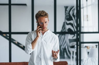 Telefonla konuşuyor. Beyaz, zarif beyaz gömlekli beyaz adam evde..