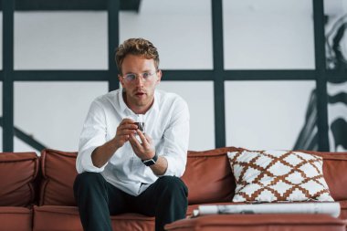 Ellerinde içkiyle. Beyaz, zarif beyaz gömlekli beyaz adam evde..