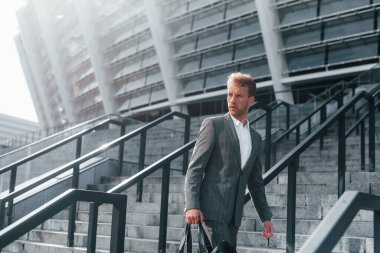 Gri üniformalı genç ve başarılı iş adamı şehirde açık havada..