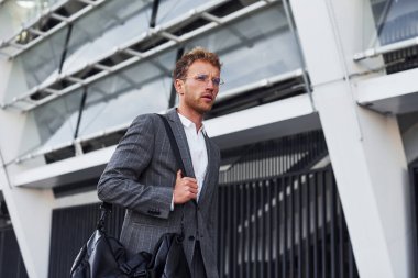 Gri üniformalı genç ve başarılı iş adamı şehirde açık havada..