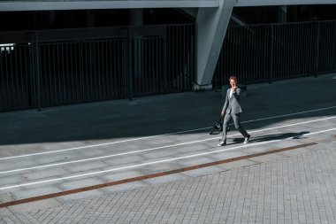 Orta parmağı gösteriyor. Gri üniformalı genç ve başarılı iş adamı şehirde açık havada..
