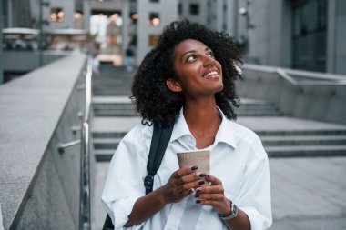 Bir bardak içkiyle. İyi giyimli Afrikalı Amerikalı kadın gündüz vakti şehir dışında..