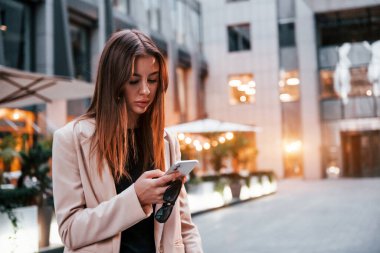 Telefon kullanıyor. Güzel genç Avrupalı kadın gündüz vakti açık havada şehirde..
