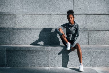 Merdivenlerde oturuyor. Spor elbiseli genç Afrikalı Amerikalı kadın gündüzleri dışarıda antrenman yapıyor..