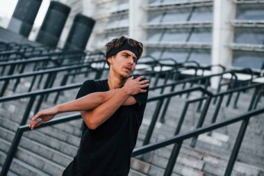 Spor elbiseli genç adam gündüz vakti dışarıda antrenman yapıyor..