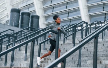 Aktif koşucu. Spor elbiseli genç Afrikalı Amerikalı kadın gündüzleri dışarıda antrenman yapıyor..