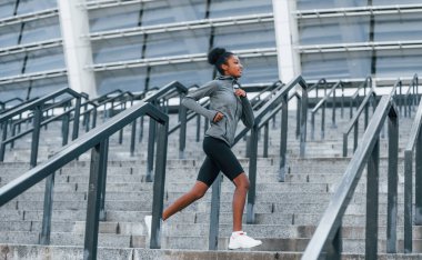 Aktif koşucu. Spor elbiseli genç Afrikalı Amerikalı kadın gündüzleri dışarıda antrenman yapıyor..