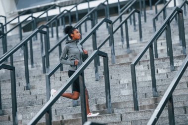 Aktif koşucu. Spor elbiseli genç Afrikalı Amerikalı kadın gündüzleri dışarıda antrenman yapıyor..