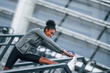 Esneme günü. Spor elbiseli genç Afrikalı Amerikalı kadın dışarıda egzersiz yapıyor..