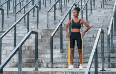 Esneme günü. Spor elbiseli genç Afrikalı Amerikalı kadın dışarıda egzersiz yapıyor..