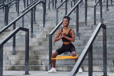 Esneme günü. Spor elbiseli genç Afrikalı Amerikalı kadın dışarıda egzersiz yapıyor..