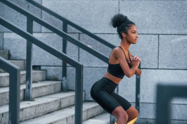 Esneme günü. Spor elbiseli genç Afrikalı Amerikalı kadın dışarıda egzersiz yapıyor..