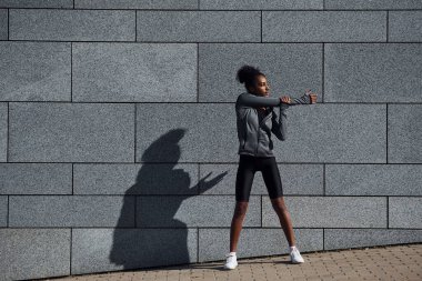 Spor elbiseli genç Afrikalı Amerikalı kadın gündüzleri dışarıda antrenman yapıyor..