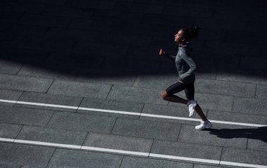 Hızlı koşucu. Spor elbiseli genç Afrikalı Amerikalı kadın gündüzleri dışarıda antrenman yapıyor..