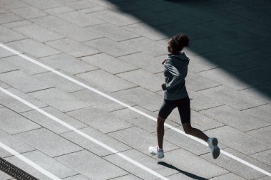 Hızlı koşucu. Spor elbiseli genç Afrikalı Amerikalı kadın gündüzleri dışarıda antrenman yapıyor..