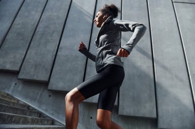 Hızlı koşucu. Spor elbiseli genç Afrikalı Amerikalı kadın gündüzleri dışarıda antrenman yapıyor..