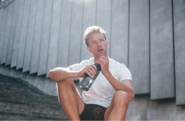 Mola veriyor. Spor elbiseli genç adam gündüz vakti dışarıda antrenman yapıyor..