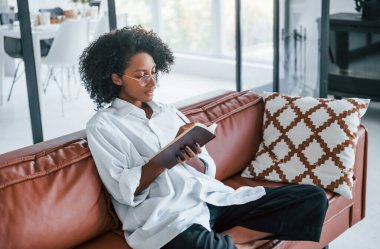 Not defteri tutuyor. Evde kıvırcık saçlı, Afro-Amerikalı bir kadın var..