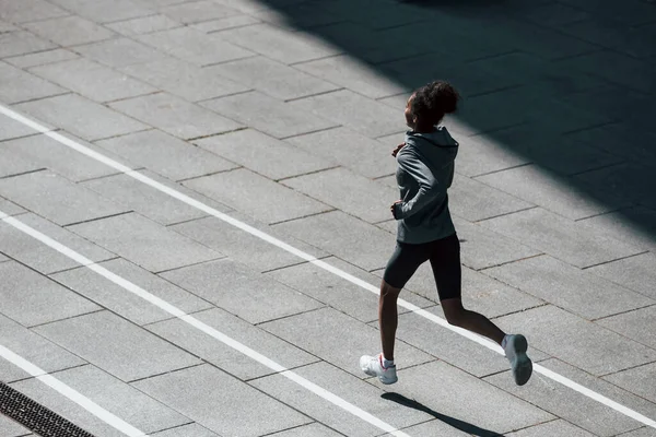 Fast runner. Young african american woman in sportive clothes have workout outdoors at daytime.