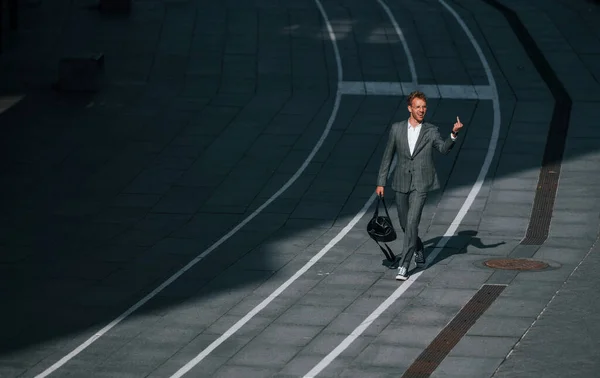 道路を歩く 灰色の正式な服を着た若いビジネスマンは街の屋外にあります — ストック写真