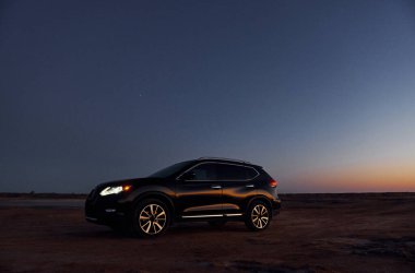 Sahildeki modern siyah otomobilin uzaktan görünüşü.