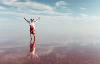 Muhteşem manzaranın tadını çıkarıyorum. Şapkalı ve günlük kıyafetli bir adam Ukrayna 'daki Jarilgach adasında gölde yürüyor..
