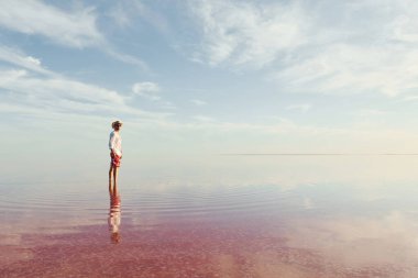 Şapkalı ve günlük kıyafetli bir adam Ukrayna 'daki Jarilgach adasında gölde yürüyor..