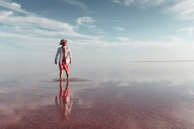 Şapkalı ve günlük kıyafetli bir adam Ukrayna 'daki Jarilgach adasında gölde yürüyor..