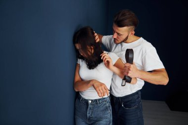 Mavi duvarın yanında. Kemerli saldırgan genç adam kız arkadaşını tehdit ediyor..