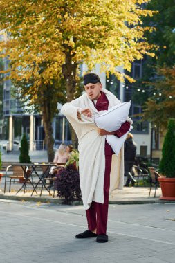 Yastığı kucaklamak. Pijamalı genç adam dışarıda, sokakta. Uykulu hissediyorum..