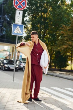 Pijamalı genç adam dışarıda, sokakta. Uykulu hissediyorum..