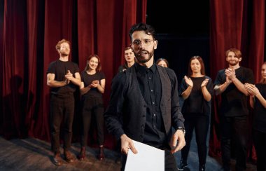 Adam rolüne çalışıyor. Tiyatroda prova yapan koyu renkli elbiseli bir grup aktör..