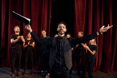 Adam rolüne çalışıyor. Tiyatroda prova yapan koyu renkli elbiseli bir grup aktör..